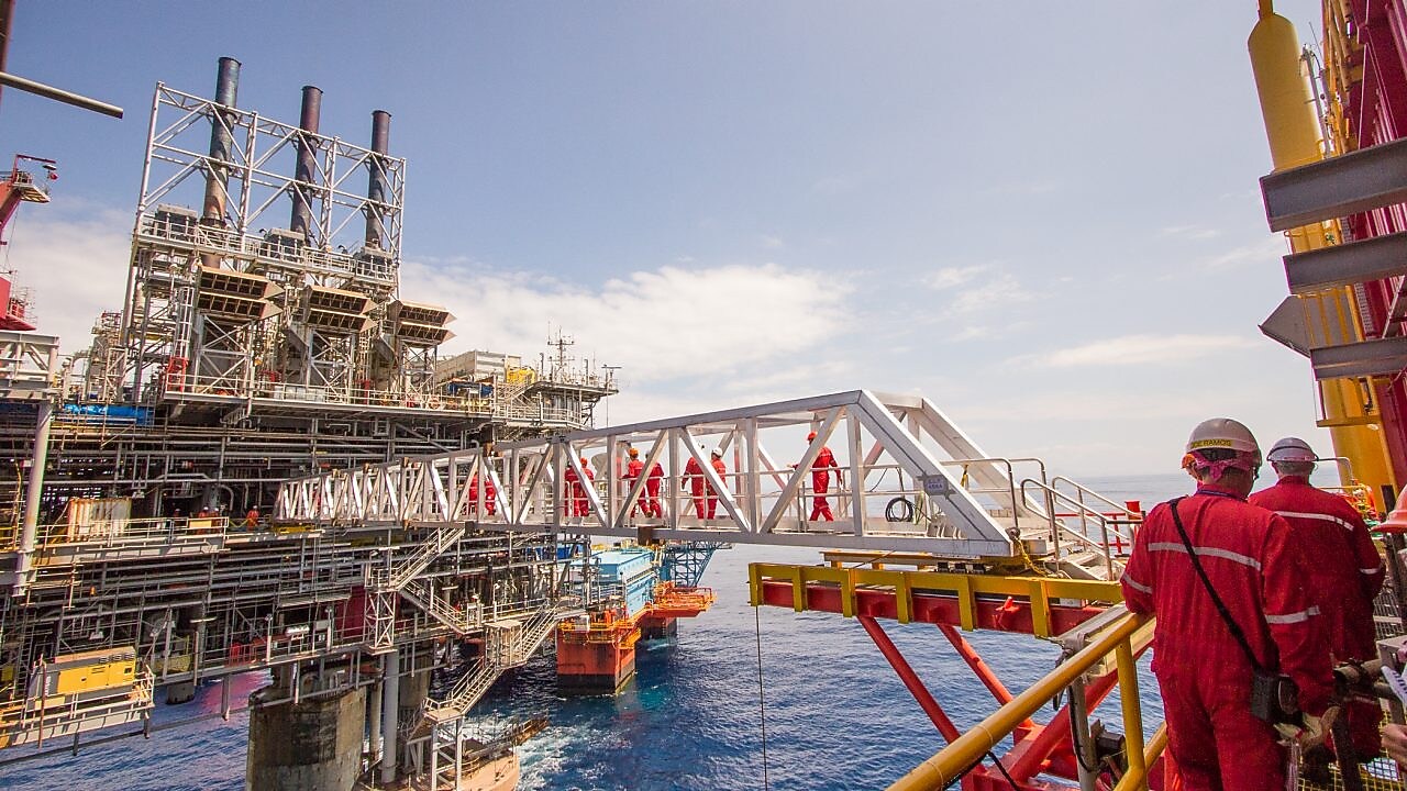 Puntorë të cilët janë duke kaluar mbi një platformë kompresioni të ndërtuar sipër projektit ekzistues të ujit, Malampaya.