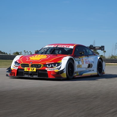 Një makinë garë BMW e kuqe dhe e bardhë ulet në pista, duke ilustruar Shell Helix Ultra dhe Partneritetin Premium të Teknologjisë së BMW